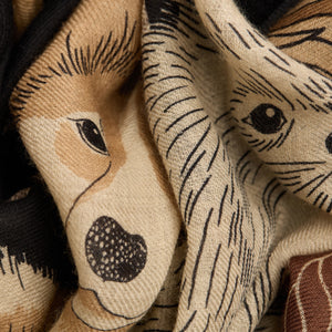 The INOUI EDITIONS - TOUTOU DOGGIE WOOL SCARF by INOUI features illustrated dogs of various breeds, sizes, and colors playfully arranged on a dark background. Made in India.