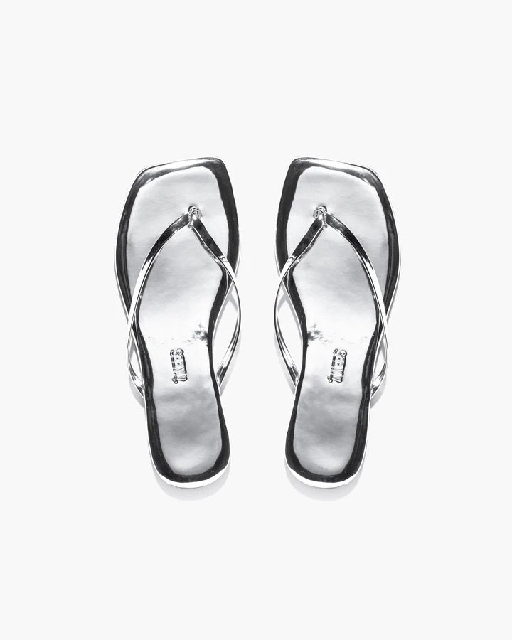 The TKEES - SQUARE TOE LILY SLIPPER MIRROR by TKEES INC features silver, square-toe sandals with thin crisscross straps in a modern style, displayed on a plain white background.