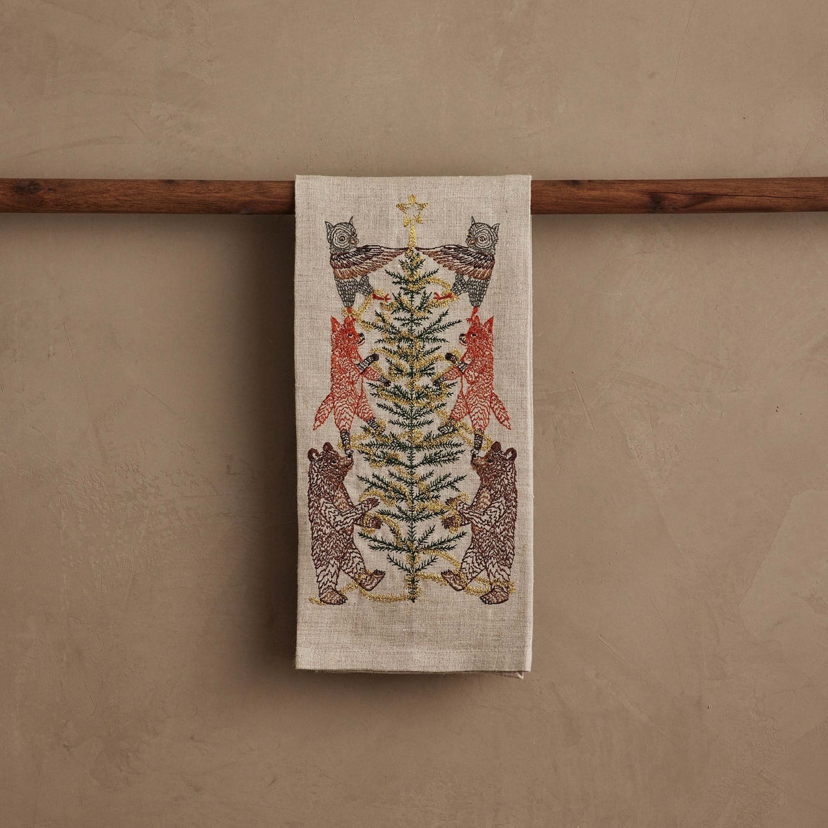 TINSEL TREE LINEN TEA TOWEL by CORAL & TUSK featuring embroidered owls, foxes, and bears decorating a tinsel tree for holiday decor.