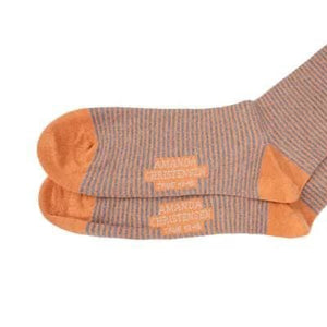 A pair of AMANDA CHRISTENSEN - TRUE STRIPE MID-CALF SOCKS IN ORANGE MELANGE, featuring Italian-made stripes in light brown and orange with solid orange toes, heels, and cuffs, are displayed overlapping on a white background. Expertly crafted by AMANDA CHRISTENSEN from soft combed cotton for enduring comfort and style.