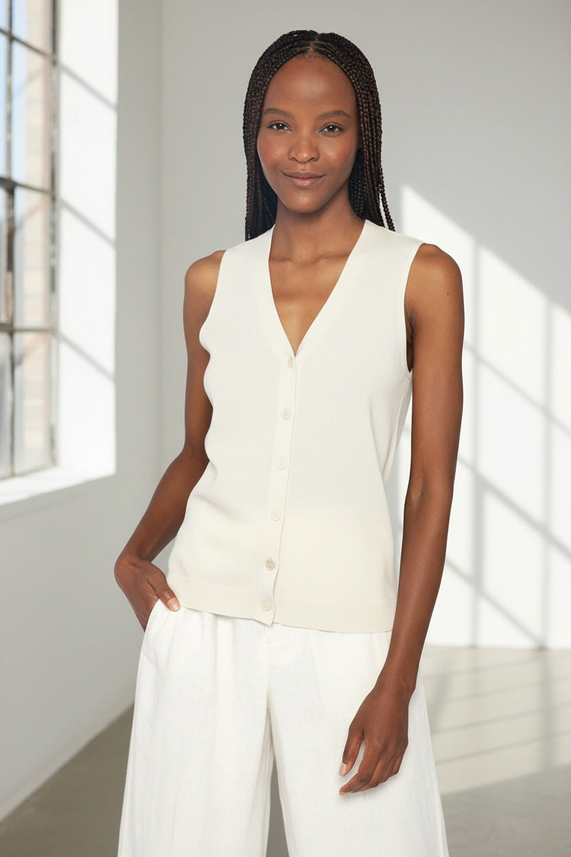 Close-up of the KINROSS CASHMERE - BUTTON VEST by KINROSS reveals a textured, off-white surface with a subtle woven pattern, evoking the refined feel of silk cashmere or a finely crafted luxury knit sweater.