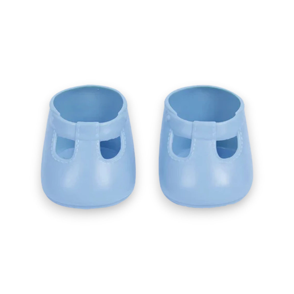 A close-up of a baby wearing OLLI ELLA USA DINKUM DOLL SHOES in Mallow Pink and white socks. The baby is seated on a soft, pale pink textured blanket, dressed in light brown clothing. Only the lower half of the baby's body is visible.