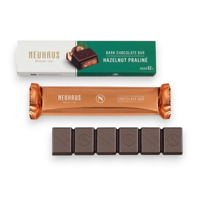 A NEUHAUS – DARK CHOCOLATE HAZELNUT BAR, crafted in Belgium, displayed in its refined wrapper and packaging, with five unwrapped pieces of dark chocolate arranged neatly in a row beneath.