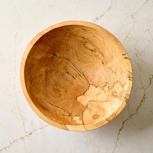 A handcrafted SPENCER PETERMAN - SPALTED MAPLE BOWL 13" by PETERMANS BOARDS & BOWLS INC, featuring a round shape with a light, natural finish and striking spalted maple grain patterns, displayed on a white background.