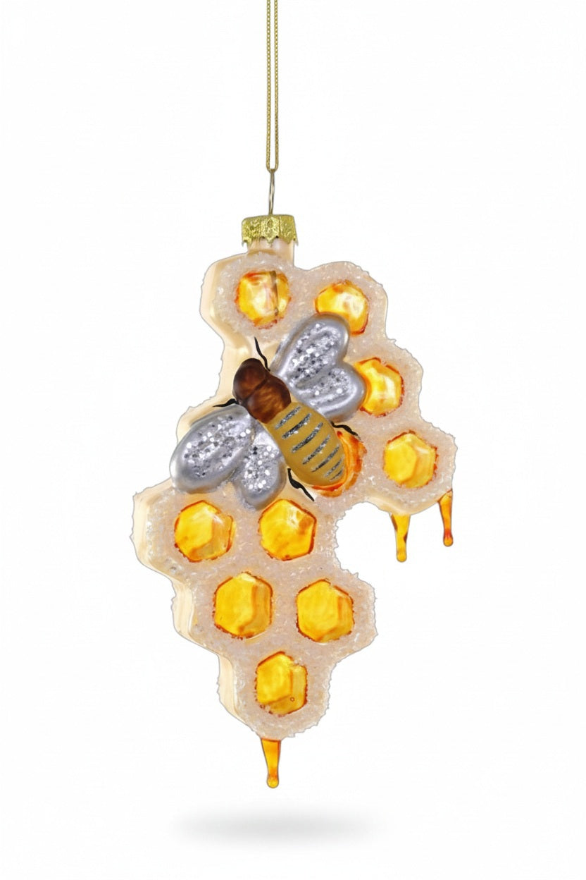 A bee rests on a 5-inch high CODY FOSTER HONEYCOMB ORNAMENT featuring a section of honeycomb with dripping honey.