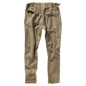 The RELWEN Supply Pant in Worker Khaki is a pair of light brown chinos inspired by classic military utility pant design, featuring side adjuster tabs, a button fly, broken twill fabric, and cuffs at the ankles with a subtly tapered leg silhouette—laid flat on a white background.