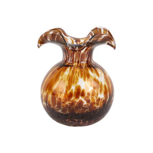 Three VIETRI decorative glass vases, including the VIETRI Hibiscus Bud Vase in Tortoiseshell, sit on a table with pink and white blossoms. Nearby, metal scissors rest on the surface.