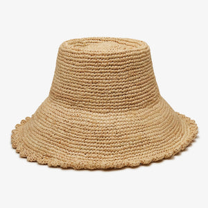 The WYETH Lacey Raffia Bucket Hat in Natural features a wide brim, textured woven pattern, and slightly scalloped edge. Displayed against a plain white background, this stylish hat is crafted by WYETH.