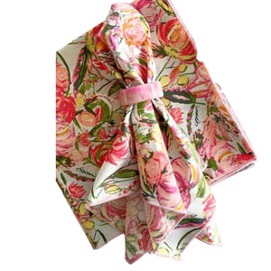 Three DOT AND ARMY FLORAL FROLIC DINNER NAPKINS in pastel pink, green, and yellow floral patterns are shown on a white surface—super soft, one is folded with a fabric napkin ring while two are stacked.