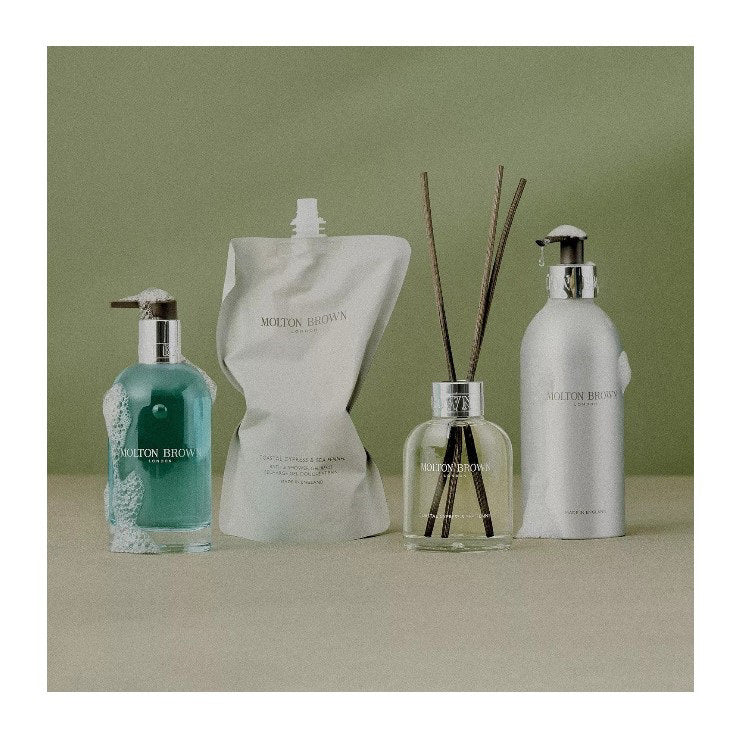 The MOLTON BROWN - COASTAL CYPRESS GLASS BOTTLE features fresh light blue hand wash in a clear bottle with a silver neck and gray pump, evoking marine notes, set against a white background.