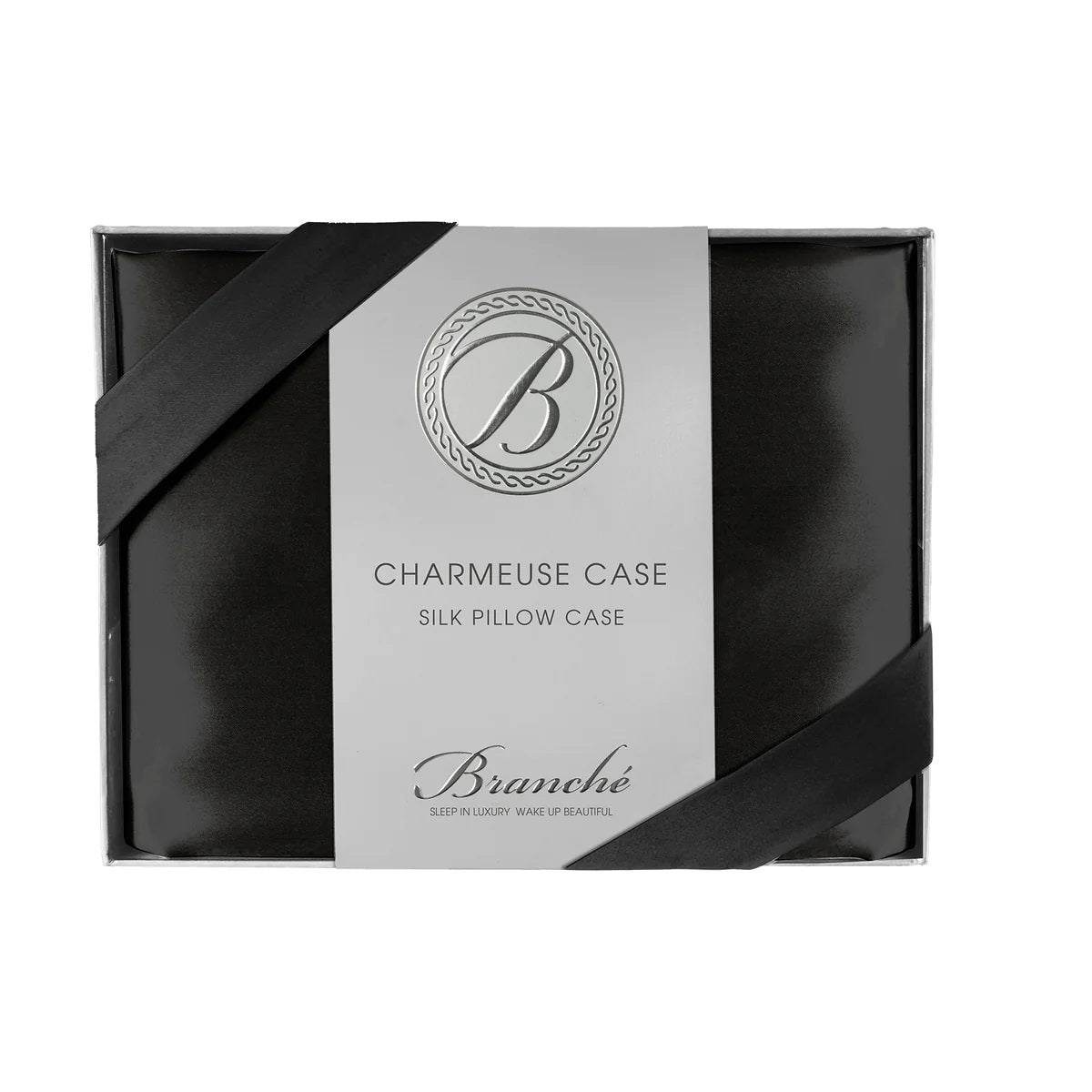 A black silk pillowcase is neatly packaged in a sleek black box with a white label that features an elegant &quot;B&quot; logo at the top. The label reads &quot;BRANCHE - CHARMEUSE PILLOW CASE SILK: Sleep in Luxury. Wake up Beautiful,&quot; while promoting skin hydration and enhancing hair care.