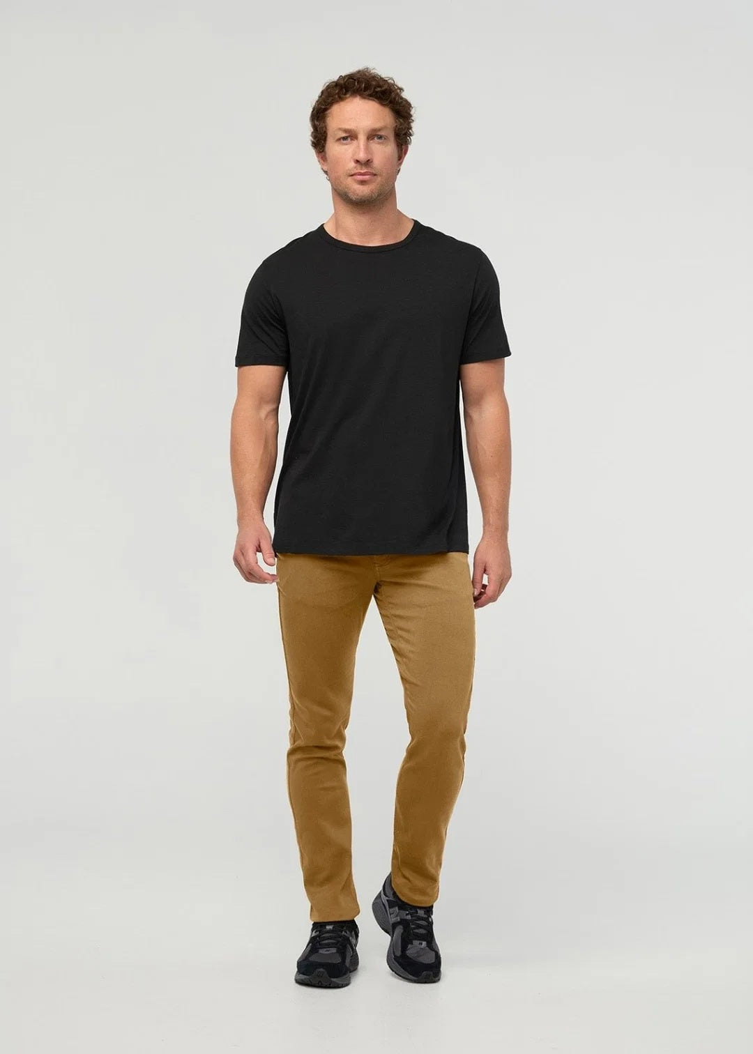 Close-up of the back of a person wearing the DUER No Sweat Straight Pants in Caramel, featuring stitched back pockets and a black DUER brand label on the waistband, crafted from DUER’s innovative No Sweat fabric for exceptional comfort.