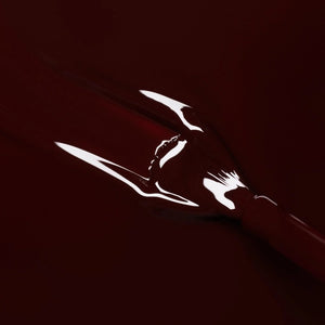 A bottle of MANUCURIST INC GREEN™ Nail Polish in the shade Hollyhock, featuring a dark burgundy color and a black cap.