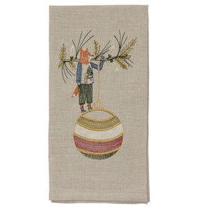 A beige linen DECK THE HALLS FOX LINEN TEA TOWEL embroidered with a fox holding a large, striped Christmas ornament, perfect for vintage Christmas kitchen decor.