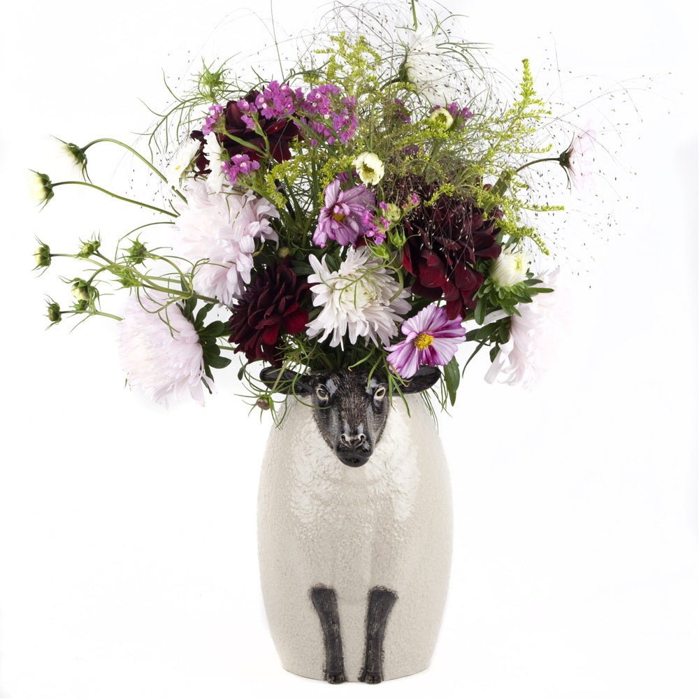The QUAIL CERAMICS - BLACK SUFFOLK SHEEP VASE by QUAIL DESIGNS is a hand-painted ceramic vase with a textured white body and detailed black face and legs, featuring a calm expression for a whimsical, artistic touch.