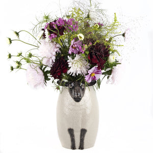 The QUAIL CERAMICS - BLACK SUFFOLK SHEEP VASE by QUAIL DESIGNS is a hand-painted ceramic vase with a textured white body and detailed black face and legs, featuring a calm expression for a whimsical, artistic touch.