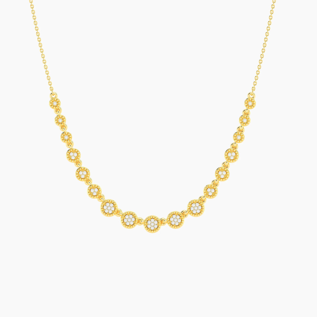A woman with blonde hair styled in a low updo wears a white off-shoulder top and the ELLA STEIN - MULTI CIRCLE CHAIN NECKLACE by ELLA STEIN, featuring gold plated chains adorned with round, sparkling floral-shaped pendants. She looks slightly down with a calm expression against a neutral background.