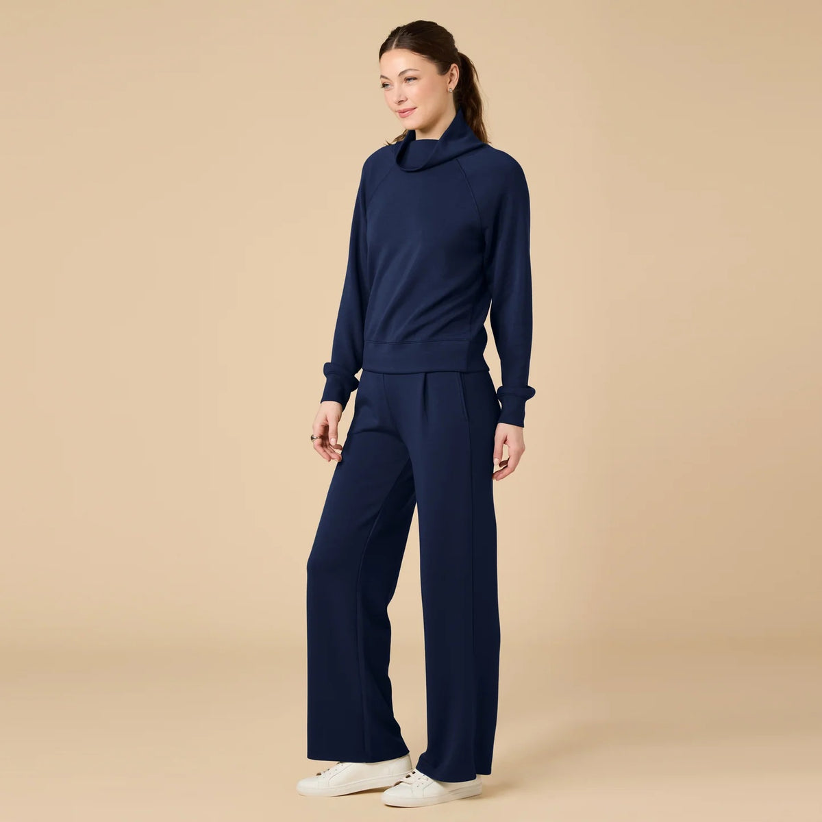 A woman seen from behind wearing the fuchsia SOFTIES - DREAMTECH COWL NECK WITH PLEATED PANT set featuring a long-sleeved cowl neck top and matching pleated pants.