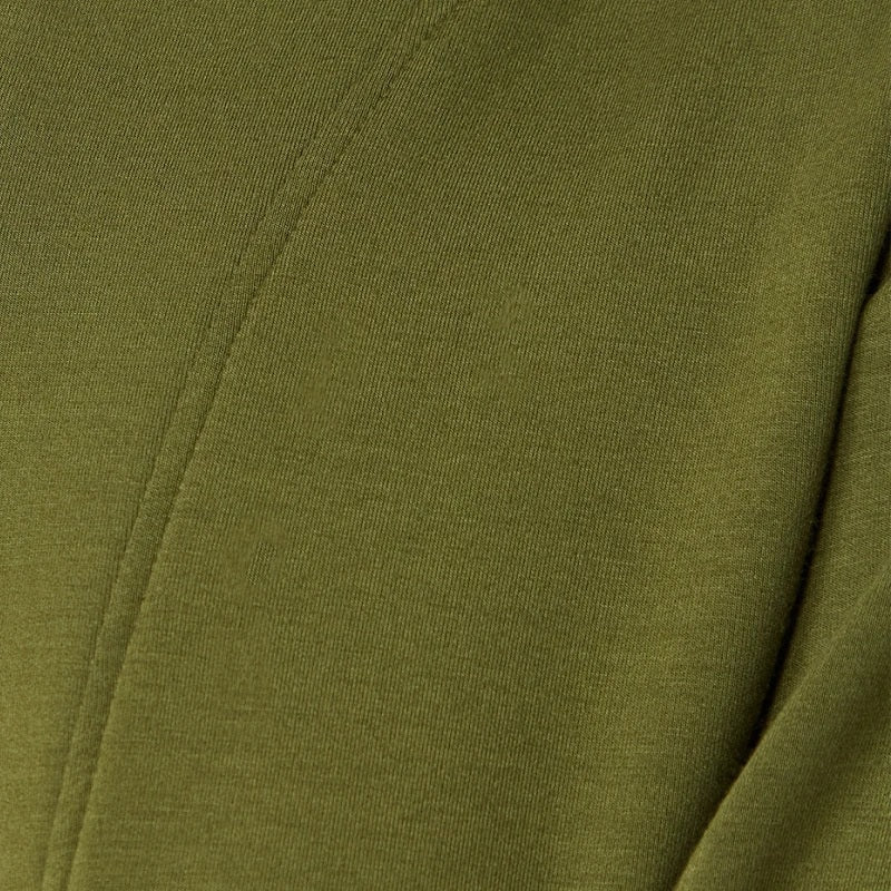 A woman wears a SOFTIES - DREAMTECH BOAT NECK WITH PINTUCK PANT SET in olive green, featuring a long-sleeve boat neck top and matching wide-leg pintuck pants.
