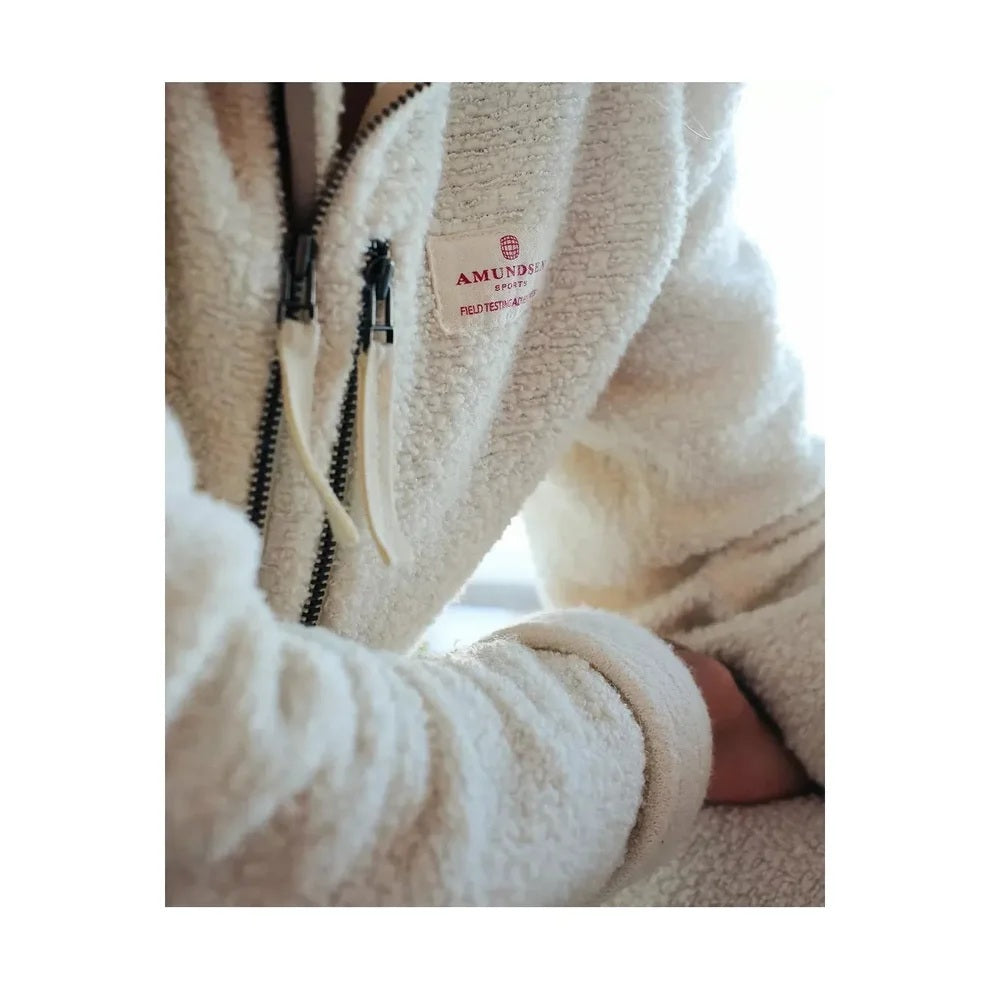 The AMUNDSEN SPORTS - HUT HALF-ZIP is a blue wool terry loop pullover with a quarter-zip neckline, zippered chest pocket, and rectangular white label above the pocket. Perfect as a cozy mid-layer sweater.