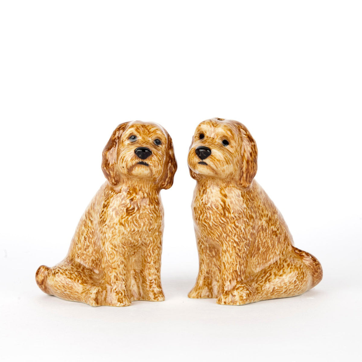 The QUAIL DESIGNS QUAIL CERAMICS - COCKAPOO SALT AND PEPPER SET features two hand-painted, golden-brown dog figurines with textured fur, sitting side by side on a white background, facing slightly forward.