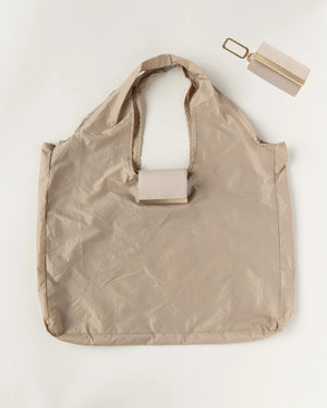 The KEOTE - KEYCHAIN TOTE IN STONE by KEOTE is a beige, lightweight, crinkled tote laid flat, with a matching rectangular pouch and keychain attachment shown above for easy storage of the reusable bag.