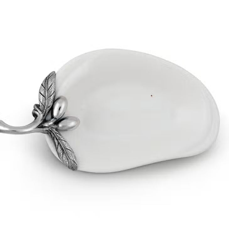 The VAGABOND HOUSE - OLIVE OIL SERVER/SPOON REST is a white, pear-shaped ceramic platter featuring a twig-like ornate metal handle adorned with pewter olives and small fruits. The handle is attached to the narrow end for an elegant touch to this minimalist design.