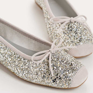 The REQINS HARMONY Sequin Ballerina Flat in Ice features a sparkling design with subtle pink trim and a small bow on the toe, shown from above against a plain light background.