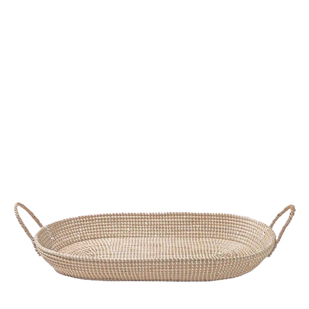The BASKET CHANGING TABLE by OLLI ELLA USA is a large, oval, woven basket featuring two handles on either end. Ideal for use as a changing basket or for nursery decor, it is crafted from light-colored natural fibers that give it a rustic and earthy appearance. The tight and uniform weave pattern ensures a sturdy base and sides, providing both durability and aesthetic appeal. The basket is empty.