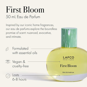A box of LAFCO - FINE FRAGRANCE, FIRST BLOOM 50ML stands among white flowers and green vines against a pale beige background.