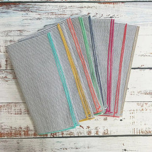 A set of DOT AND ARMY - GREY SEERSUCKER DINNER NAPKINS, each with colorful edging, is fanned out on a white background.