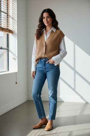 A woman wears the KINROSS CASHMERE Rib Button Knit Vest over a white shirt and blue jeans, standing with one hand in her pocket against a plain white background.