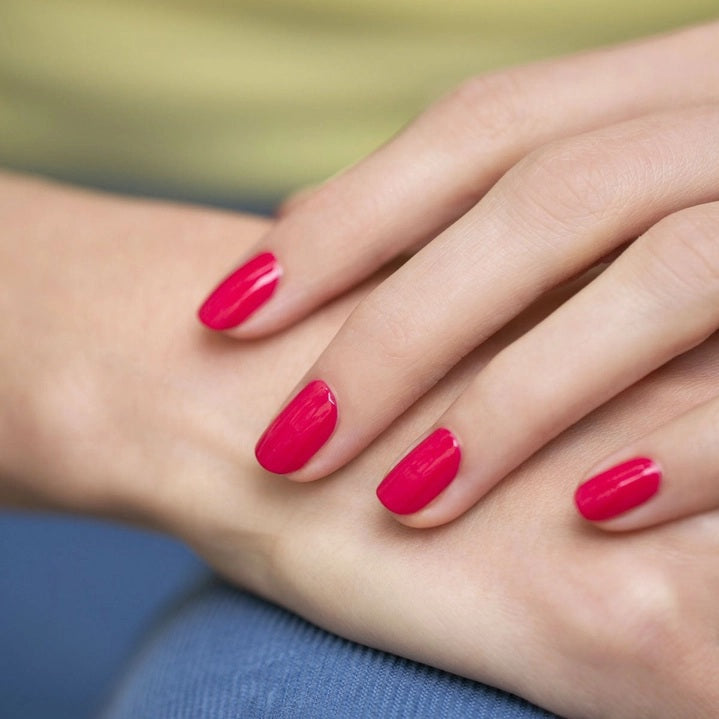 A bottle of MANUCURIST INC’s GREEN™ Nail Polish in the shade Peony, featuring a black cap and pink color visible through the clear glass.