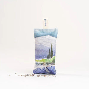 The L'AUGUSTE PROVENCE - FRENCH LAVENDER SACHET FROM PROVENCE is a small handcrafted pouch with a countryside watercolor design, upright shape, "L'AUGUSTE PROVENCE" tag, and dried lavender pieces at its base.