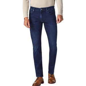 A man wearing a beige long-sleeve polo shirt, 34 HERITAGE - COURAGE STRAIGHT LEG JEAN IN DARK MIDNIGHT BRUSHED URBAN WASH by 34 HERITAGE, and brown dress shoes stands against a white background.