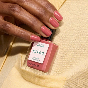 A close-up of a brush applying the smooth, glossy MANUCURIST - GREEN™ NAIL POLISH IN ROSEWOOD by MANUCURIST INC in a dusty pink rosewood shade on a flat surface, creating gentle curved lines in the polish.