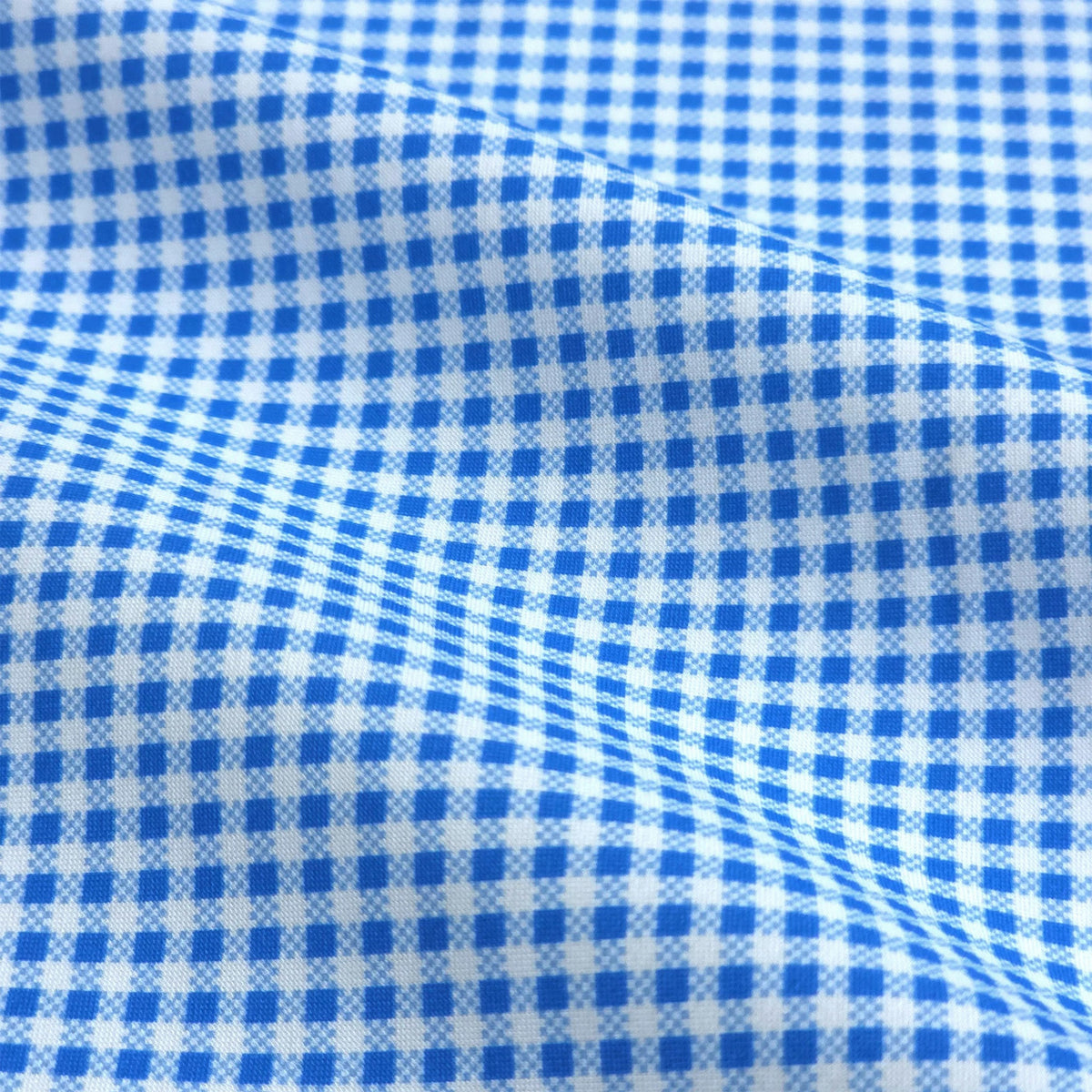 A man with short dark hair and a trimmed beard, wearing the COLLARS AND CO - Oxford Button Down Collar Apex Performance Dress Shirt in Micro Blue Gingham, holds open a glass door and looks left in a bright, modern space.