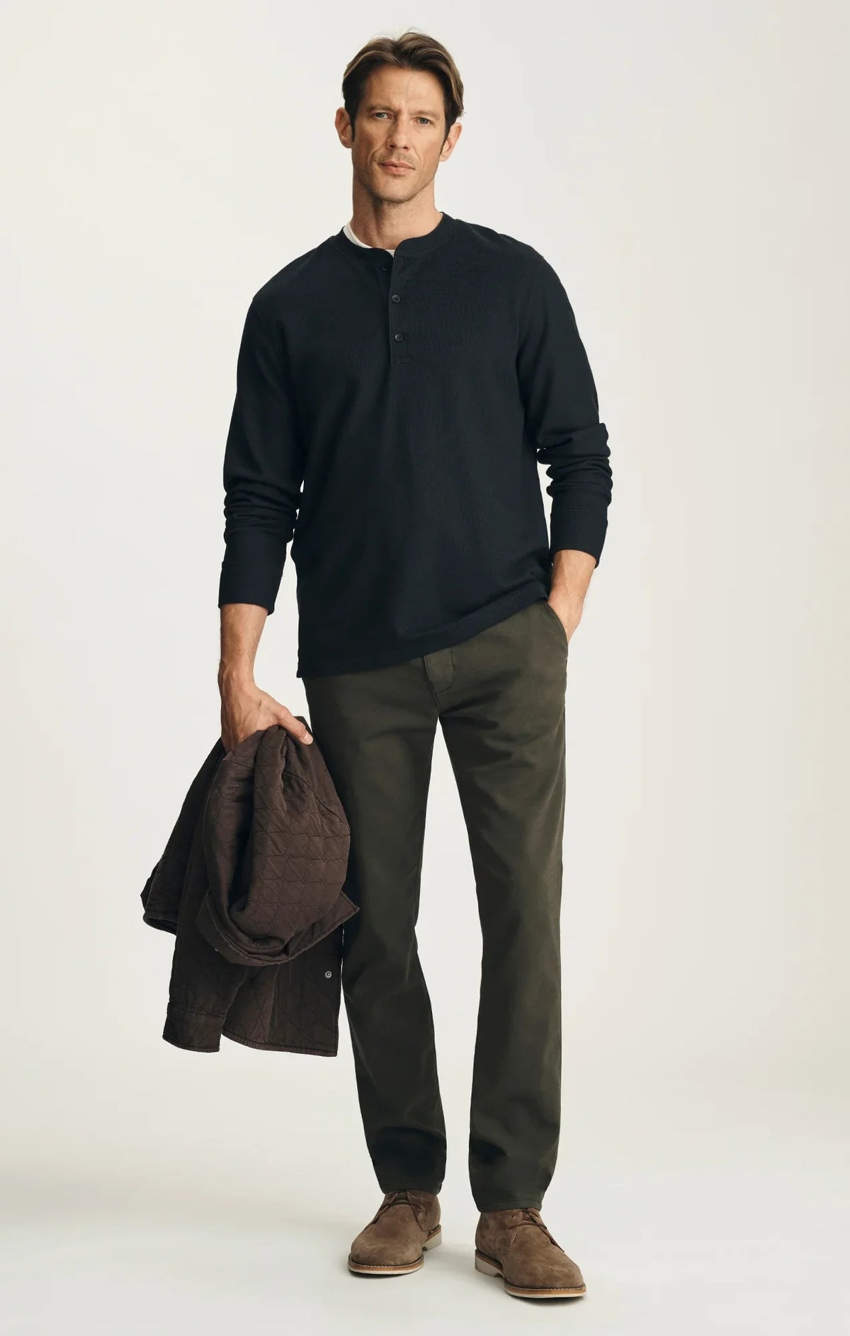 A person stands with their back to the camera against a neutral background, wearing the 34 HERITAGE - VERONA Straight Leg Chino Pant in Jasper High Flyer paired with a black long-sleeve shirt and brown suede shoes.