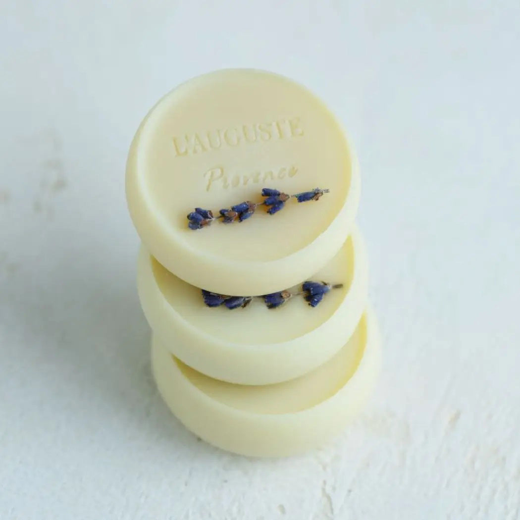 The L&#39;AUGUSTE PROVENCE gift box holds four round artisanal lavender soaps, each wrapped in blue and purple watercolor paper, with one organic soap outside the white box and ivy leaves accenting the left side.