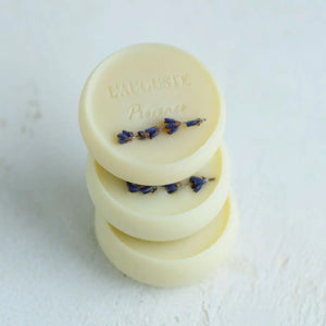 The L'AUGUSTE PROVENCE gift box holds four round artisanal lavender soaps, each wrapped in blue and purple watercolor paper, with one organic soap outside the white box and ivy leaves accenting the left side.
