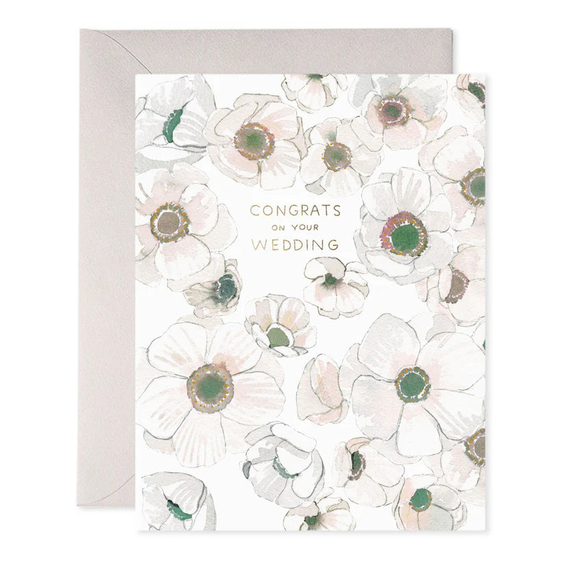 The E. FRANCES PAPER - WHITE FLOWER WEDDING CARD features watercolor-style white flowers with "Congrats on your wedding" in elegant gold lettering on the front, capturing the charm of an artisanal greeting card. An envelope peeks from behind it.