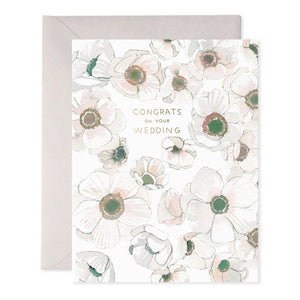 The E. FRANCES PAPER - WHITE FLOWER WEDDING CARD features watercolor-style white flowers with "Congrats on your wedding" in elegant gold lettering on the front, capturing the charm of an artisanal greeting card. An envelope peeks from behind it.