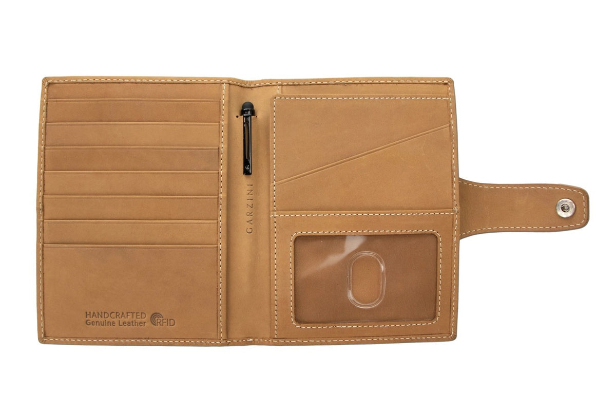 The GARZINI RFID-blocking leather passport holder in camel brown features white stitching and a circular front compartment for an Apple AirTag.