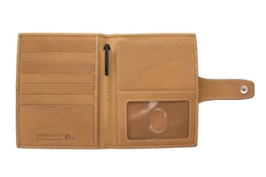 The GARZINI RFID-blocking leather passport holder in camel brown features white stitching and a circular front compartment for an Apple AirTag.