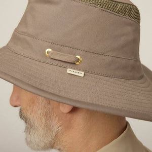 A man with a gray beard and mustache wears the TILLEY Airflo Hikers Hat T4MO-1 in olive, featuring UPF 50+ sun protection, and a beige button-up shirt, looking directly at the camera against a plain light background.
