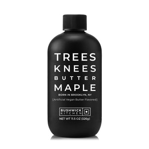A bottle of "Trees Knees Butter Maple Syrup" by Bushwick Kitchen, originated in Brooklyn, NY. The label indicates it's artificially flavored vegan butter and gluten-free. The black bottle with white text has a capacity of 11.5 oz (326g) and features a black screw-on cap.