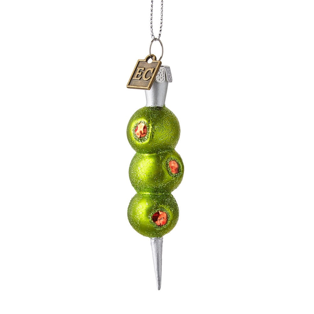The THREE OLIVES PLEASE ORNAMENT by RAZ IMPORTS is a 3.5-inch glass decoration featuring three green olives with red pimento centers stacked on a silver cocktail pick, topped with a small gold &quot;EC&quot; tag.