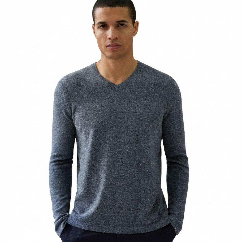 A man with short hair stands against a plain white background with his hands in his pockets, wearing the AUTUMN CASHMERE Basic Cashmere V Neck with Open Bottom in Cobble.