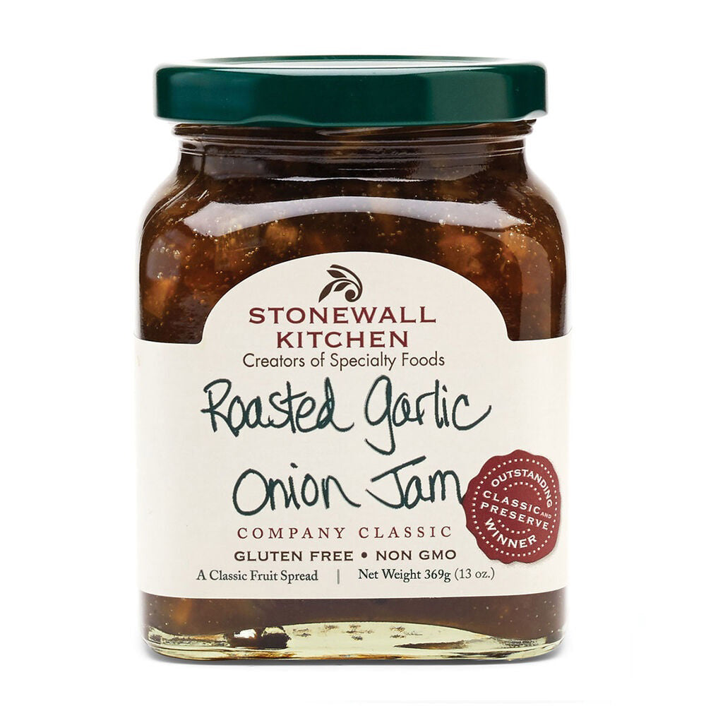 A jar of STONEWALL KITCHEN - ROASTED GARLIC ONION JAM, celebrated for its savory balance. The label reveals it is gluten-free, non-GMO, and weighs 13 ounces (369 grams). Featuring a green lid, this product is described as a classic fruit spread. An award seal can be seen on the right side of the label.