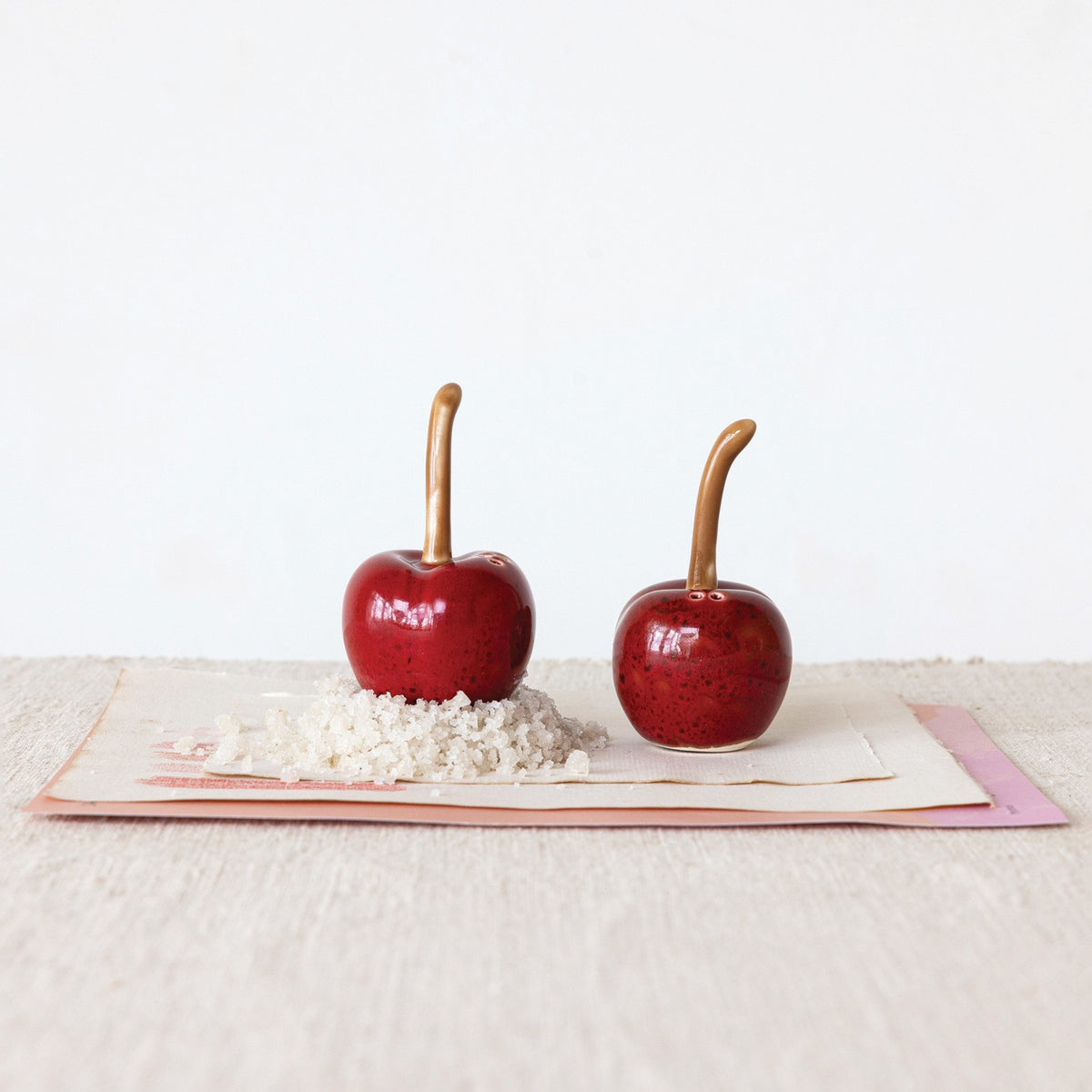 Add a charming touch to your kitchen with CREATIVE COOP’s STONEWARE CHERRY SHAPED SALT AND PEPPER SHAKERS—dark red ceramic cherries with brown stems, perfect for vintage decor.